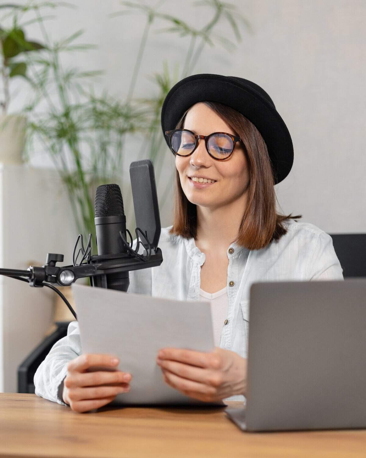 modern millennial woman in a stylish hat in the studio or at home records a podcast or a radio