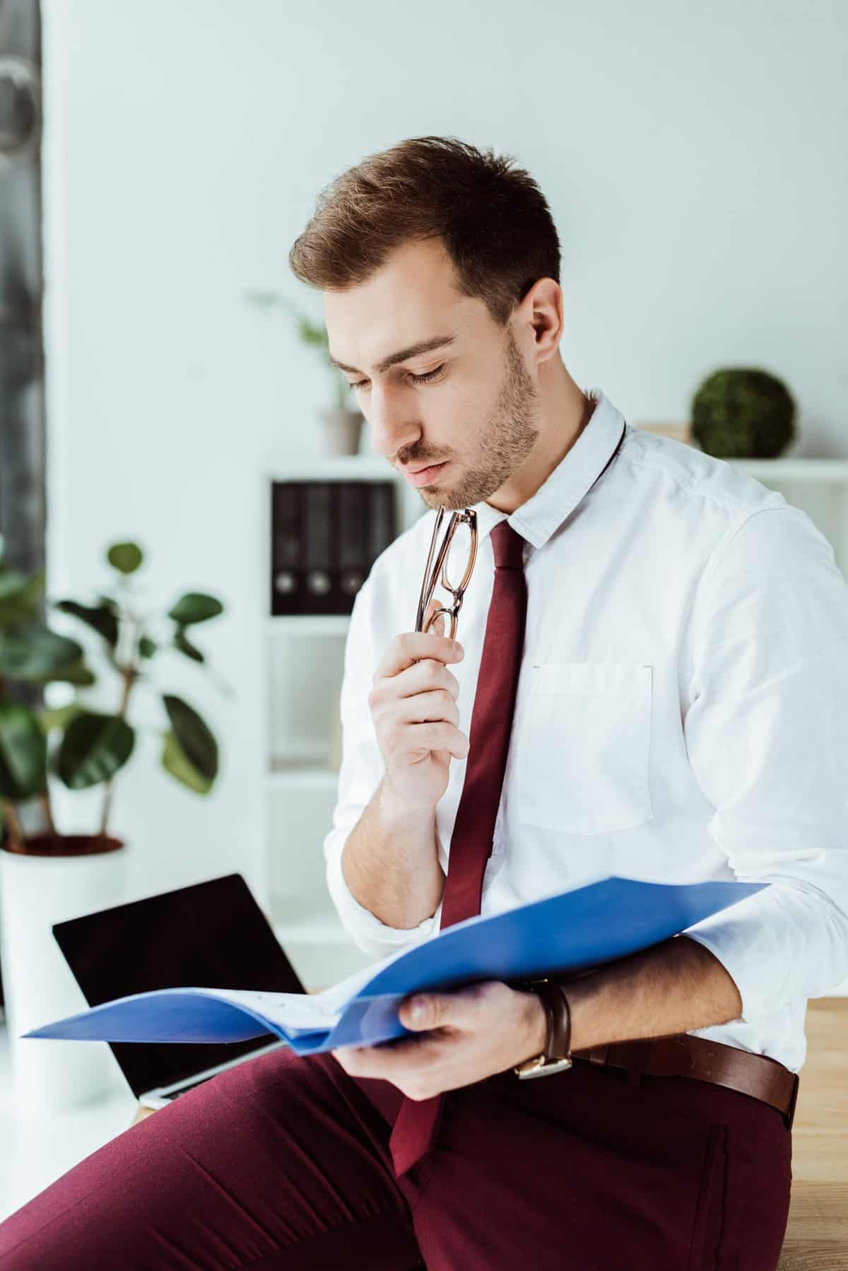 pensive businessman reading documents from folder